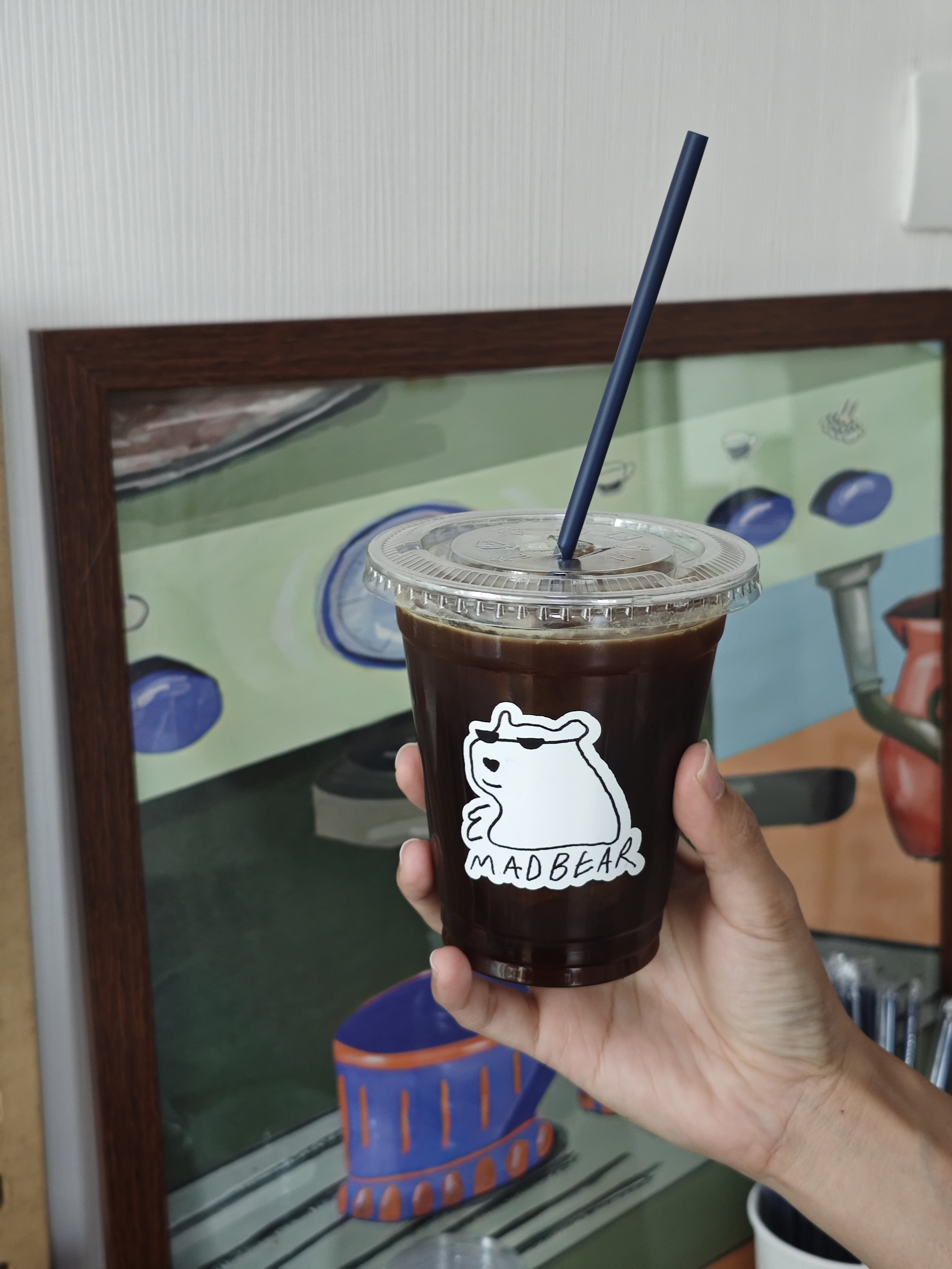 Hand holding an iced Madbear coffee